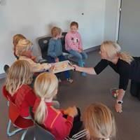 Barn som sit i ring rundt ein vaksen - Klikk for stort bilde